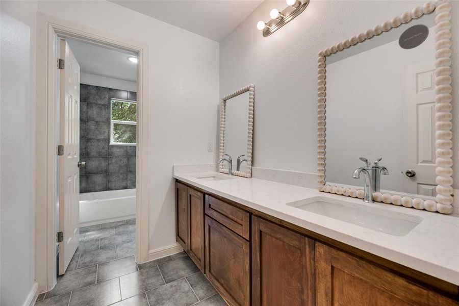 Bathroom with tile patterned flooring, vanity, and tiled shower / bath