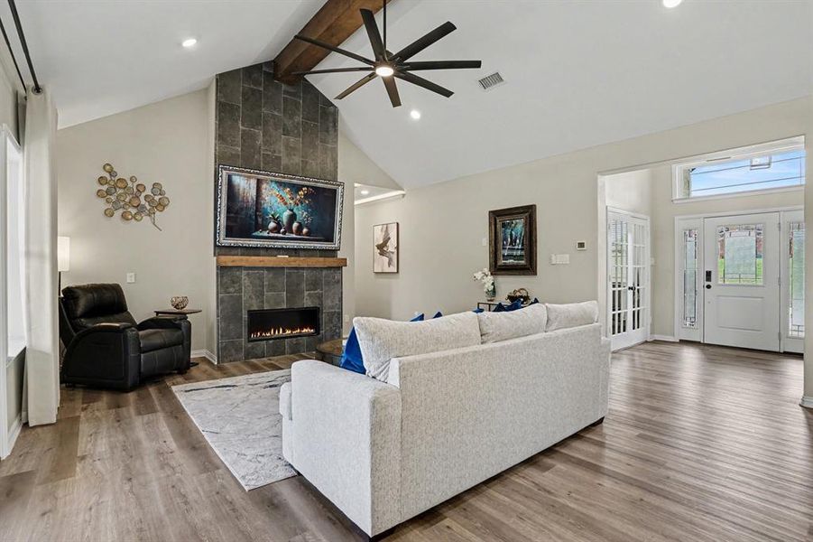 Living area with vaulted ceiling,  light wood-style floors, ceiling fan, a tile fireplace, and recessed lighting