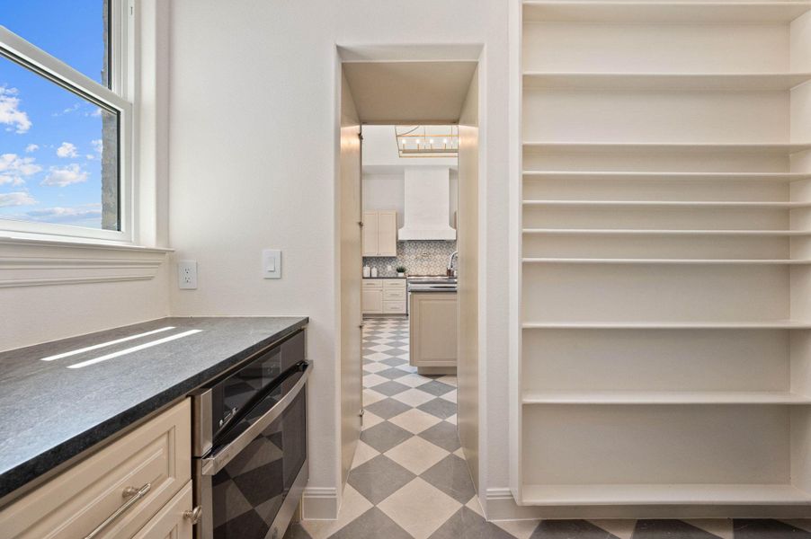 Kitchen with cream cabinetry, oven, backsplash, light floors, and dark stone counters