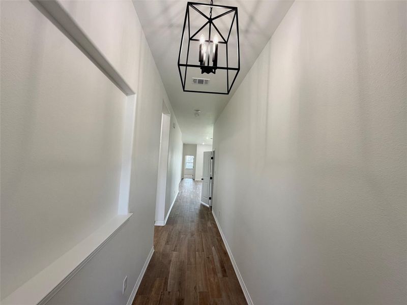 Hallway featuring wood-finish flooring, white painted walls, and a black geometric ceiling light fixture