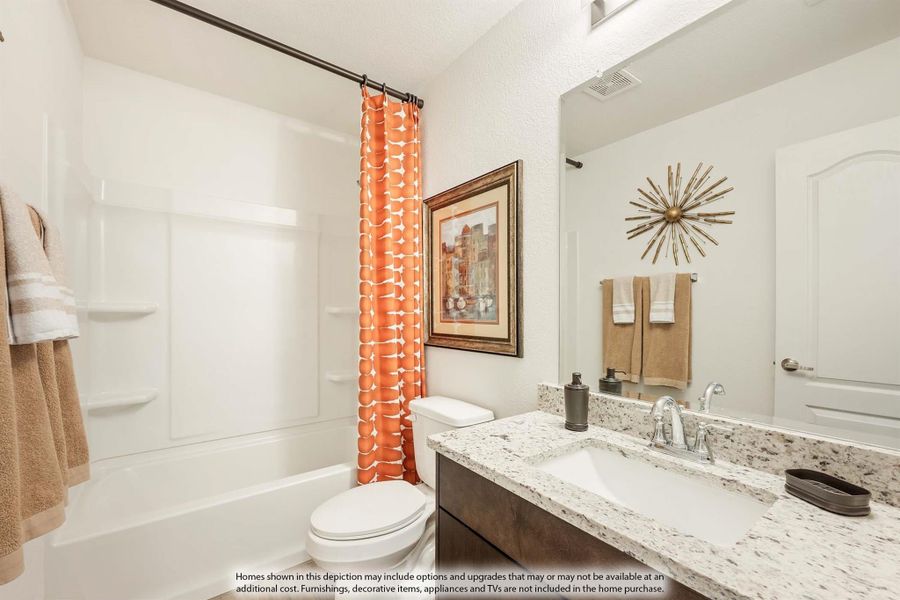 Bathroom with granite countertop vanity, white tub and shower with orange curtain, and large mirror