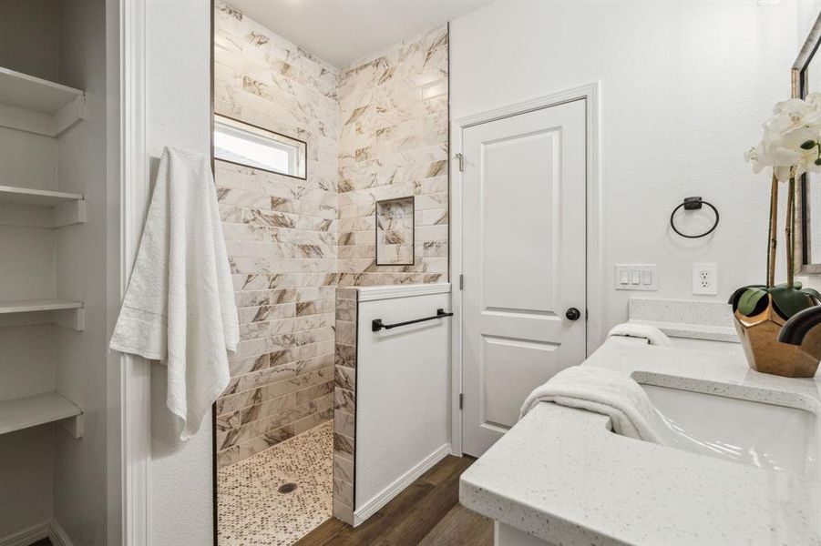 Bathroom with tiled shower, hardwood / wood-style flooring, and dual bowl vanity