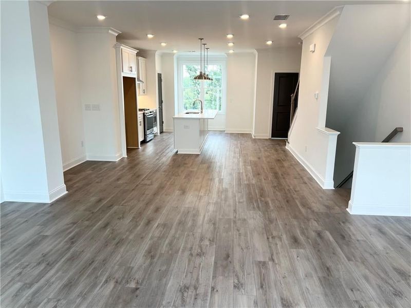 Unfurnished living room with wood finished floors, ornamental molding, and recessed lighting