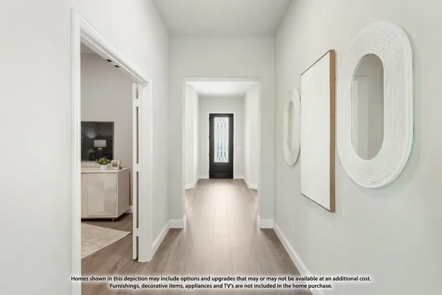 Bright entryway hallway with wood-look floors, black front door, and decorative mirrors on white walls