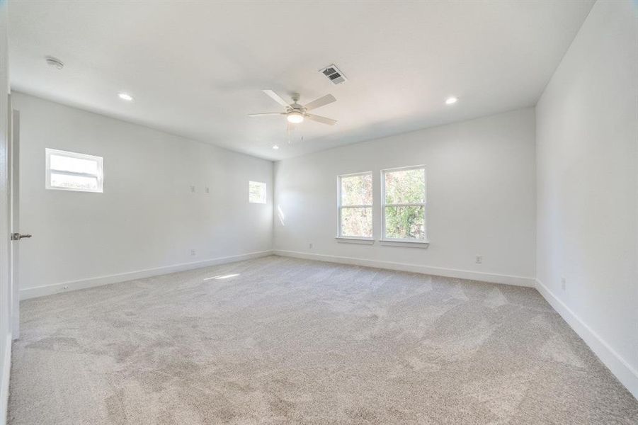 Spare room featuring ceiling fan, light carpet, and a healthy amount of sunlight