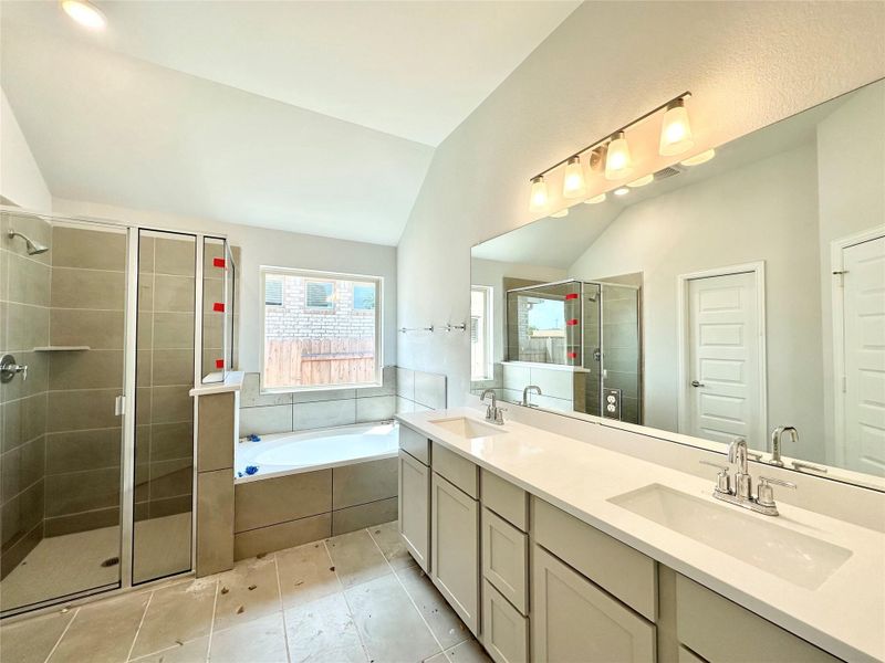 Full bathroom with a shower stall, a garden tub, double vanity, vaulted ceiling, and tile patterned floors Full bathroom with a shower stall, a garden tub, double vanity, vaulted ceiling, and tile patterned floors