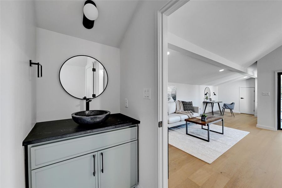 Bathroom with vanity, vaulted ceiling, and wood-type flooring