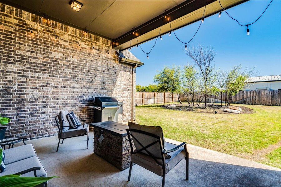 Fenced backyard featuring a patio, area for grilling, and a fire pit Fenced backyard featuring a patio, area for grilling, and a fire pit