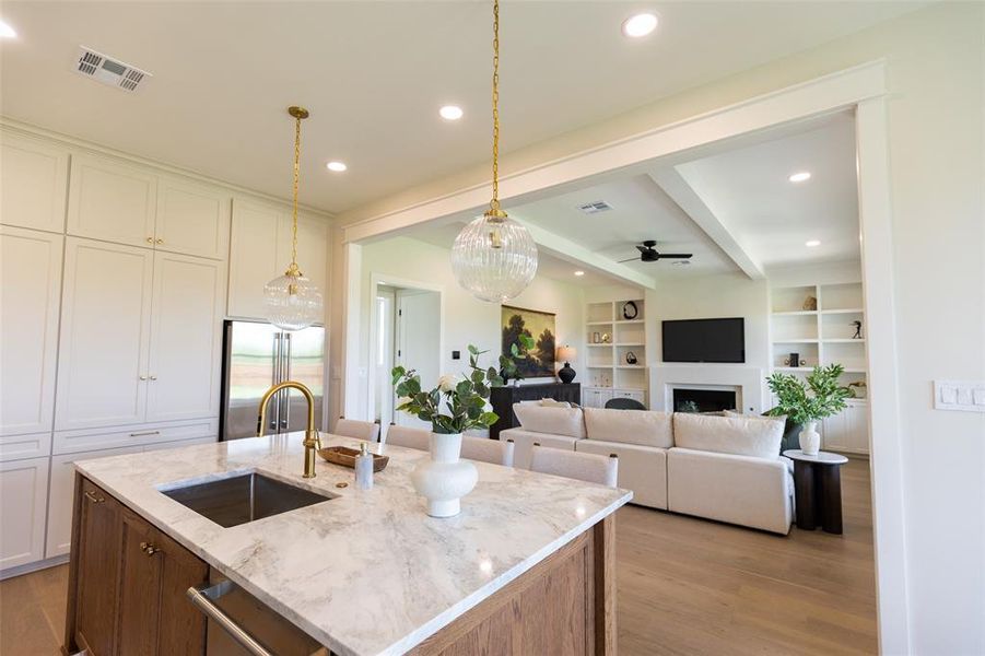 Kitchen island with a light-toned stone countertop, integrated sink, and gold-finish faucet