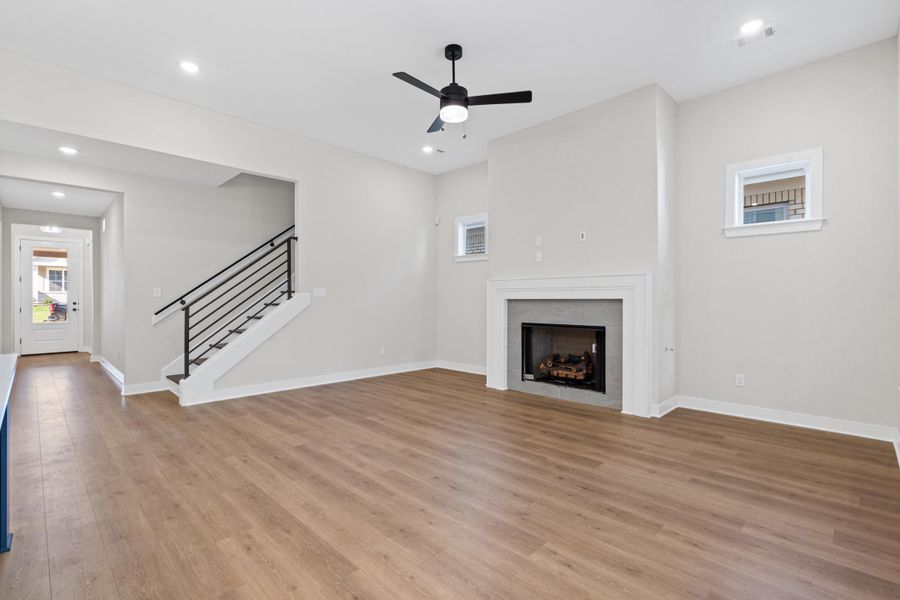 Spacious interior with wood-finish flooring, a contemporary fireplace, and a modern staircase with black railings Spacious interior with wood-finish flooring, a contemporary fireplace, and a modern staircase with black railings