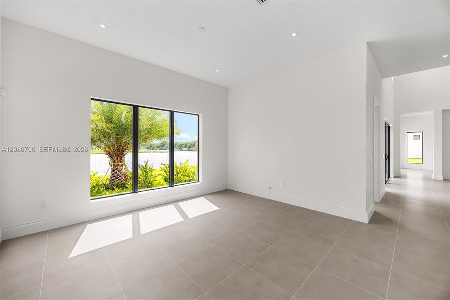 Large window with a black frame, recessed lighting, light-toned tile flooring, and white painted walls