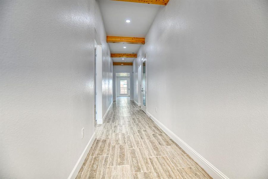 Corridor featuring beamed ceiling and light hardwood / wood-style floors