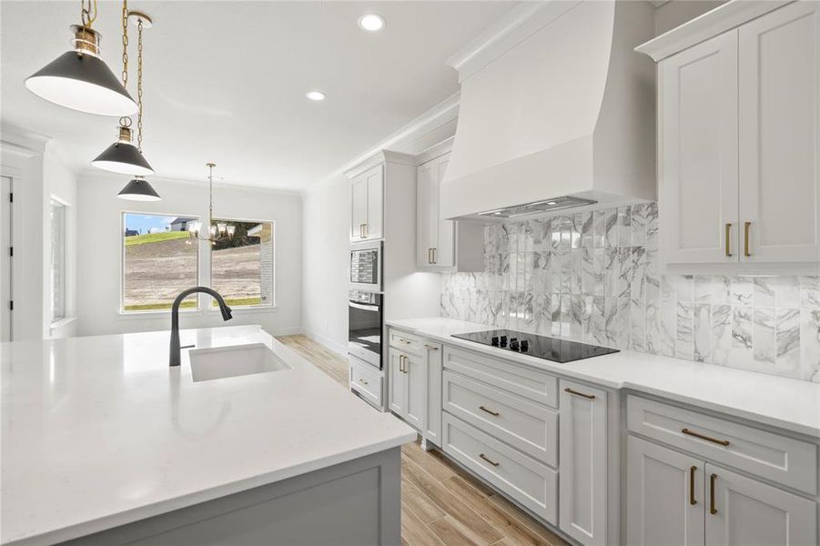 Kitchen with decorative light fixtures, custom exhaust hood, light wood-style flooring, a chandelier, and white cabinetry