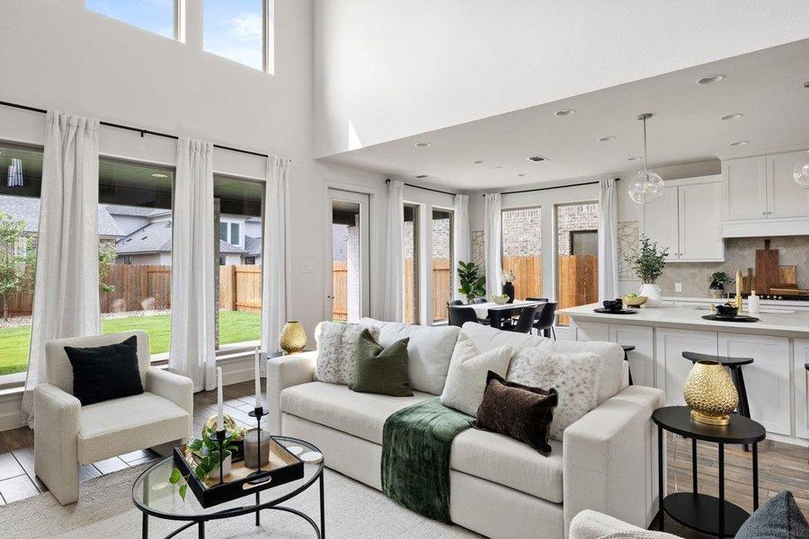 Natural illumination fills this open-concept living space with high ceilings and verdant outdoor views.