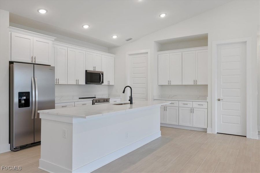 Kitchen featuring stainless steel appliances, lofted ceiling, white cabinets, wood finish floors, and recessed lighting
