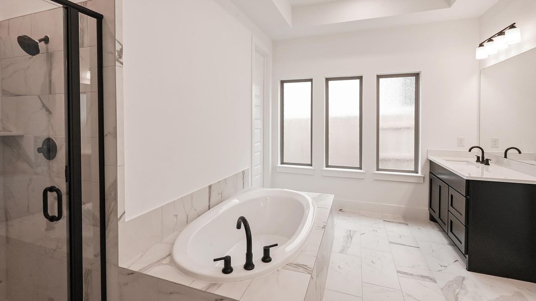 Bathroom with a bath, a shower stall, vanity, baseboards, and marble finish flooring Bathroom with a bath, a shower stall, vanity, baseboards, and marble finish flooring