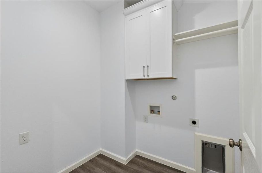 Dedicated utility area featuring white shaker-style cabinetry, a built-in hanging rod, LVP flooring, and hookups for full size washer & dryer.