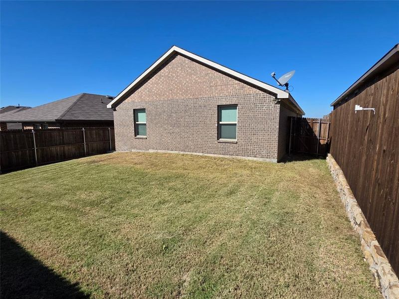 Rear view of property with a fenced backyard and brick siding Rear view of property with a fenced backyard and brick siding