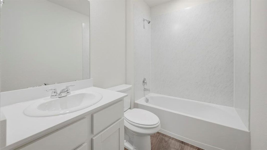 Bathroom featuring vanity, shower / washtub combination, and dark wood-style flooring