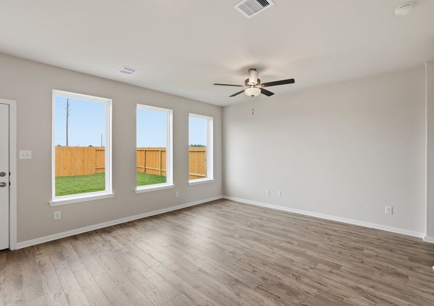 Angled view of the family room showing windows, a ceiling fan, and wood-look vinyl flooring.