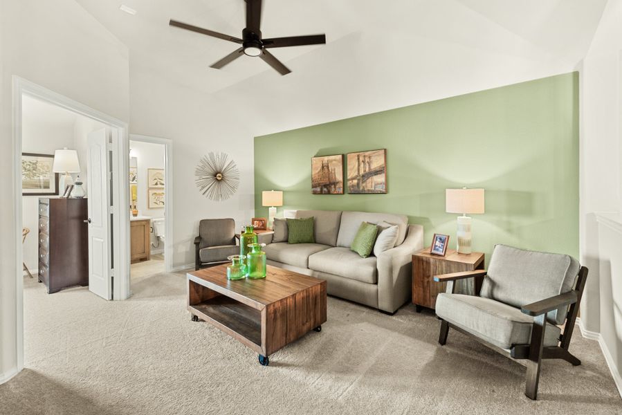 Living room with green accent wall, ceiling fan, gray sofa, and wood coffee table on carpet