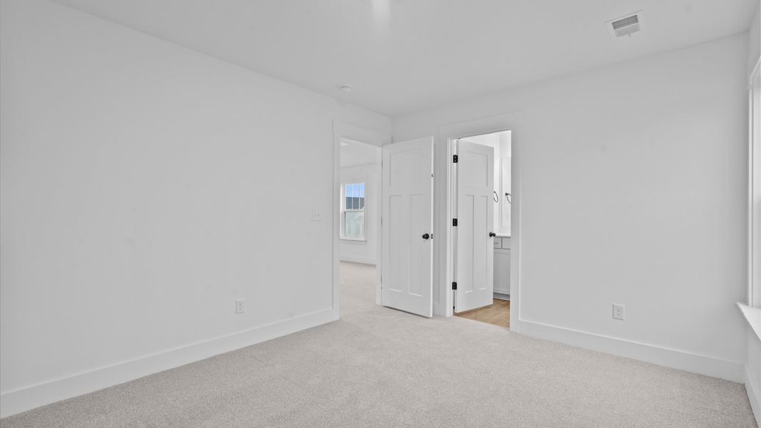 Elegant bedroom retreat featuring soft carpet and oversized windows that create a bright, welcoming space