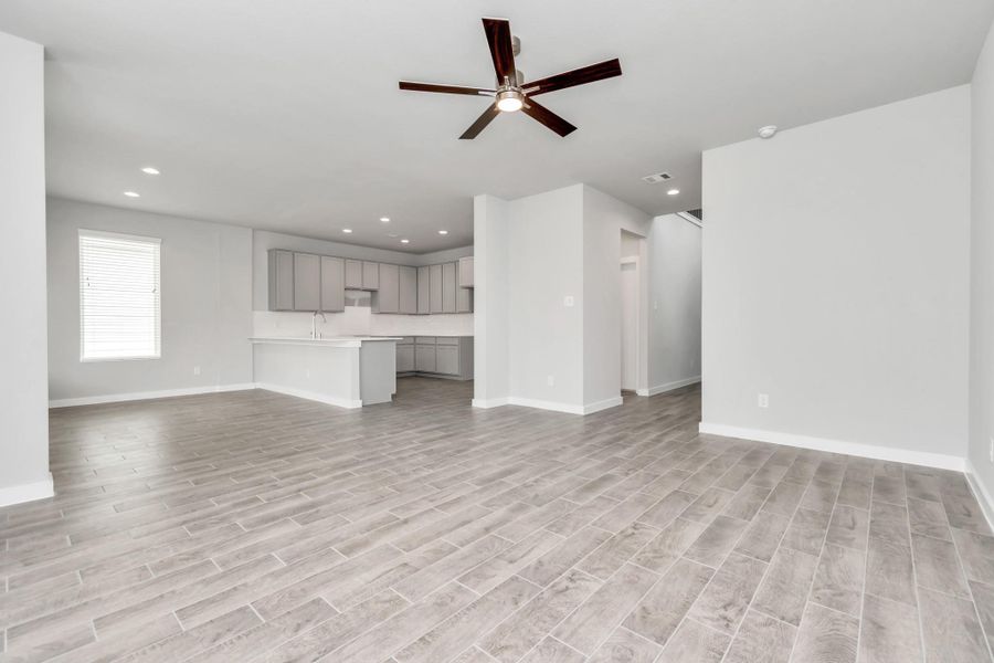 Welcome family and guests to your charming living room! With its high ceilings, recessed lighting, ceiling fan, custom paint, beautiful flooring, and large windows that let in abundant natural light, this room is perfect for gatherings. Sample photo of completed home with similar floor plan. Actual colors and selections may vary.