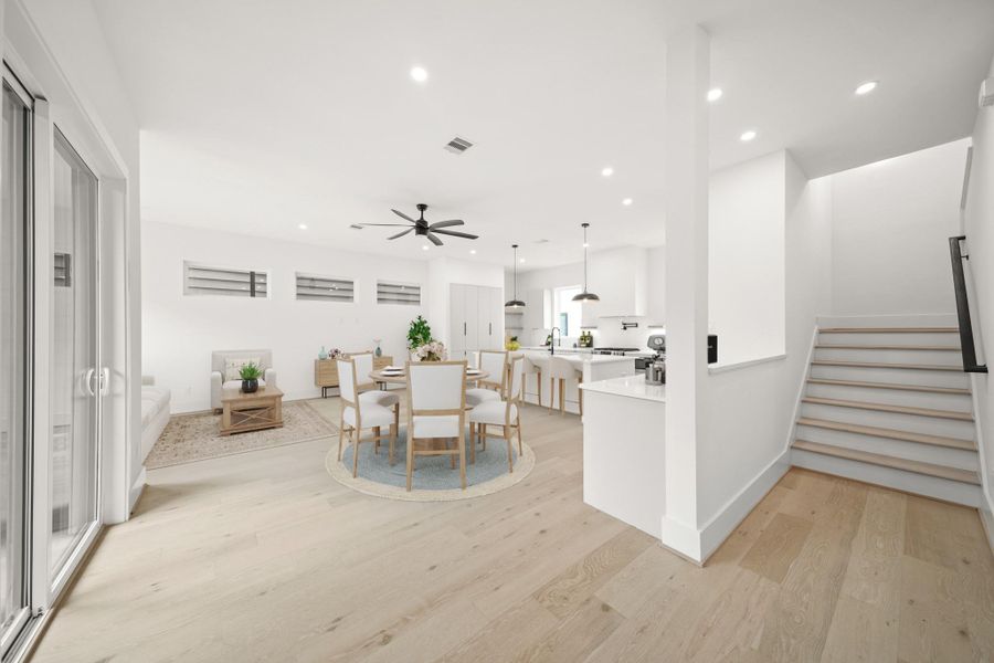 Perfect for daily living and entertaining, this custom home features an open layout with an abundance of natural light that connects the kitchen, dining, family room and nearby half bath. This photo has been virtually staged.