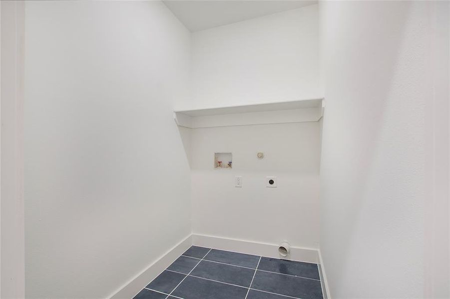 Washroom featuring washer hookup, hookup for an electric dryer, dark tile patterned floors, and hookup for a gas dryer