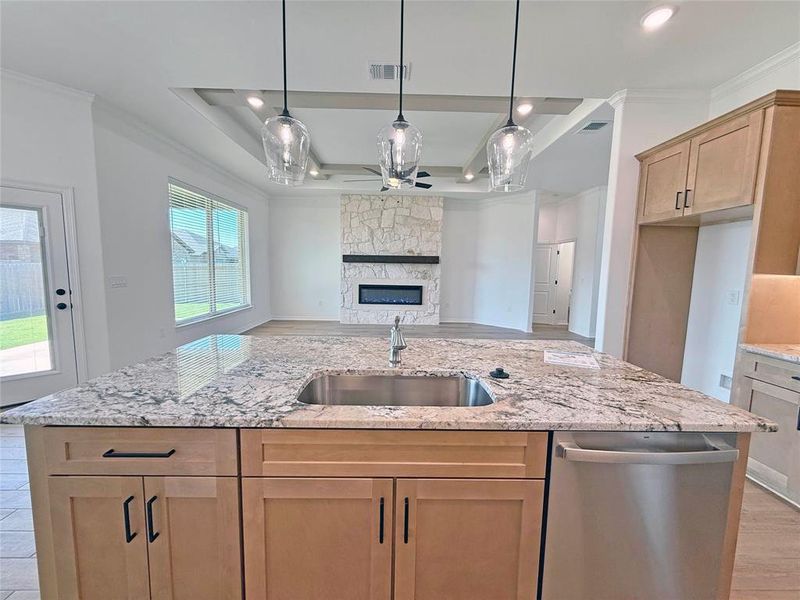 Kitchen featuring stainless steel dishwasher, crown molding, light stone countertops, decorative light fixtures, and light wood-style floors