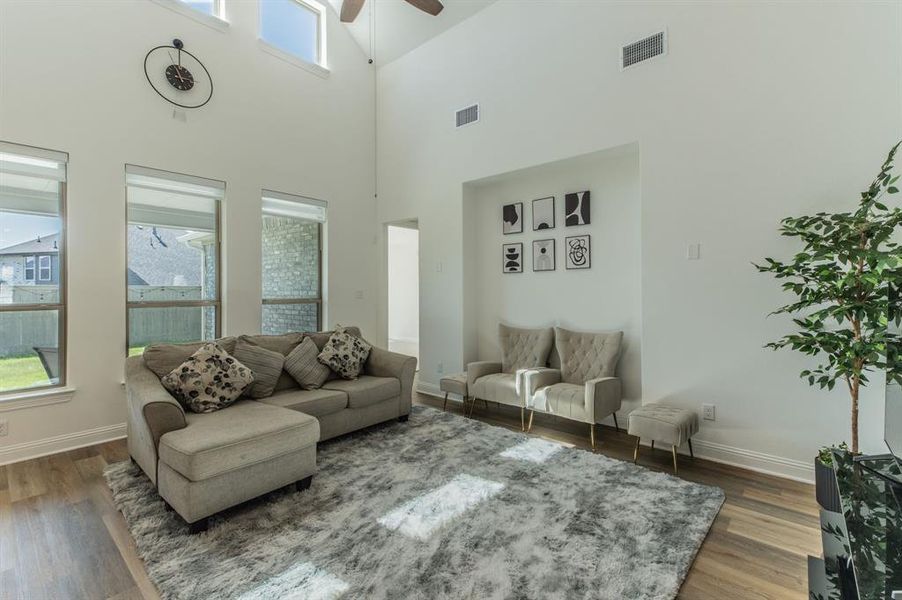 Spacious living area featuring high ceilings, upper transom windows, recessed wall niche, and wood-finish flooring