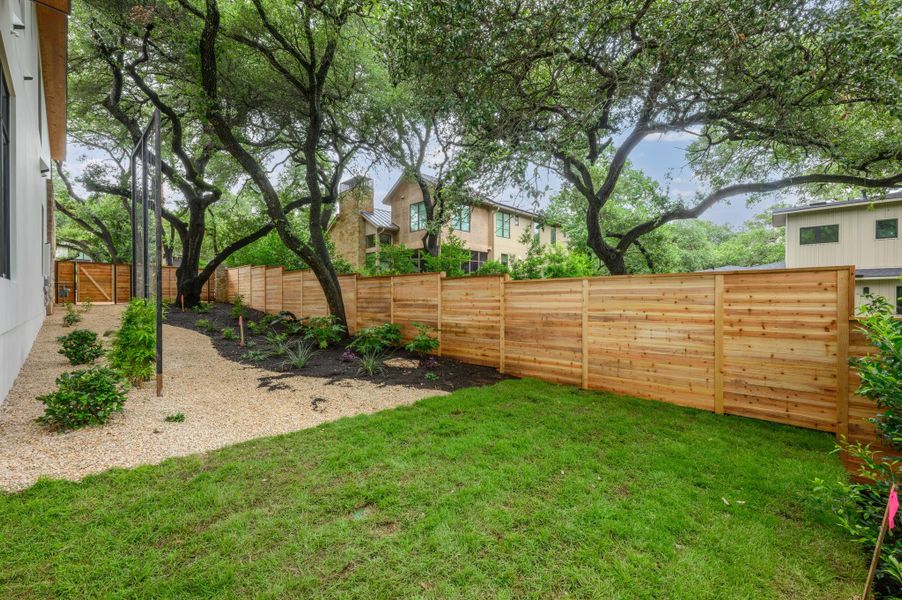 A private yard with a new wooden fence provides a serene outdoor space amidst mature trees. A private yard with a new wooden fence provides a serene outdoor space amidst mature trees.