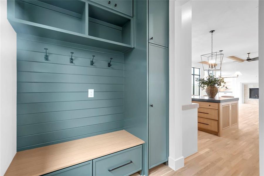 Mudroom with light wood finished floors, a ceiling fan, a fireplace, and suspended lighting Mudroom with light wood finished floors, a ceiling fan, a fireplace, and suspended lighting