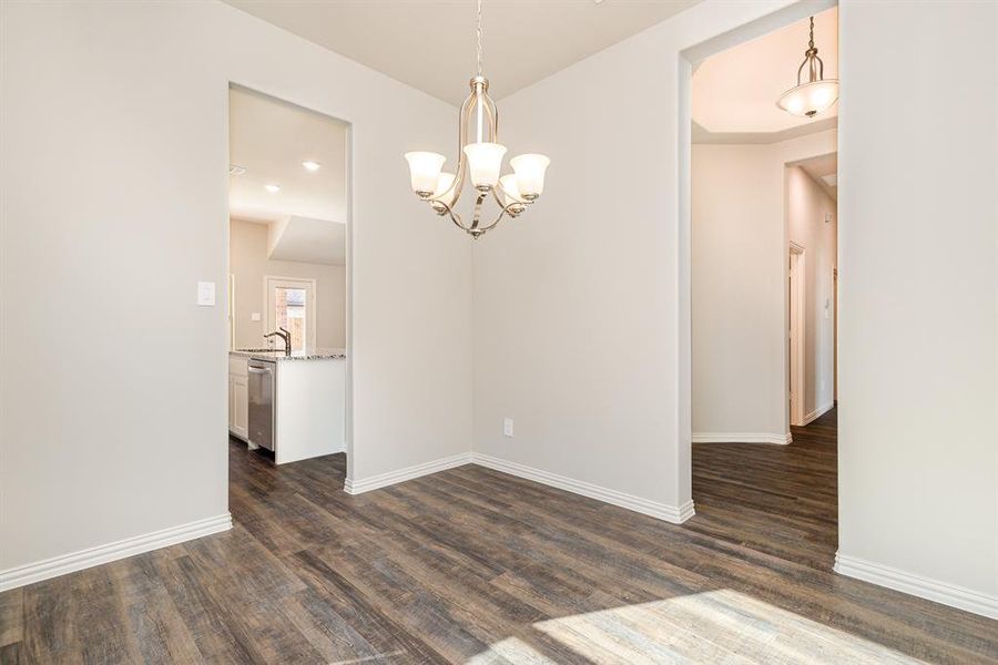 Unfurnished dining area featuring dark hardwood / wood-style flooring, an inviting chandelier, and sink