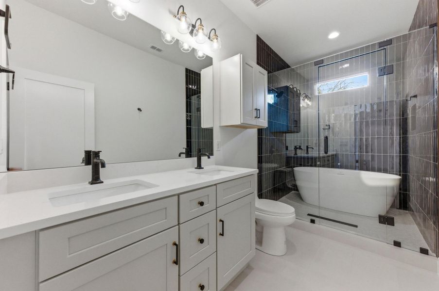 Full bathroom featuring double vanity, a stall shower, and a freestanding tub