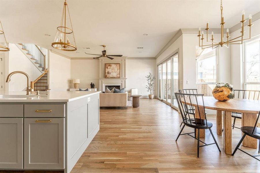 Kitchen featuring hanging lights, a ceiling fan, gray cabinetry, light wood finished floors, and ornamental molding