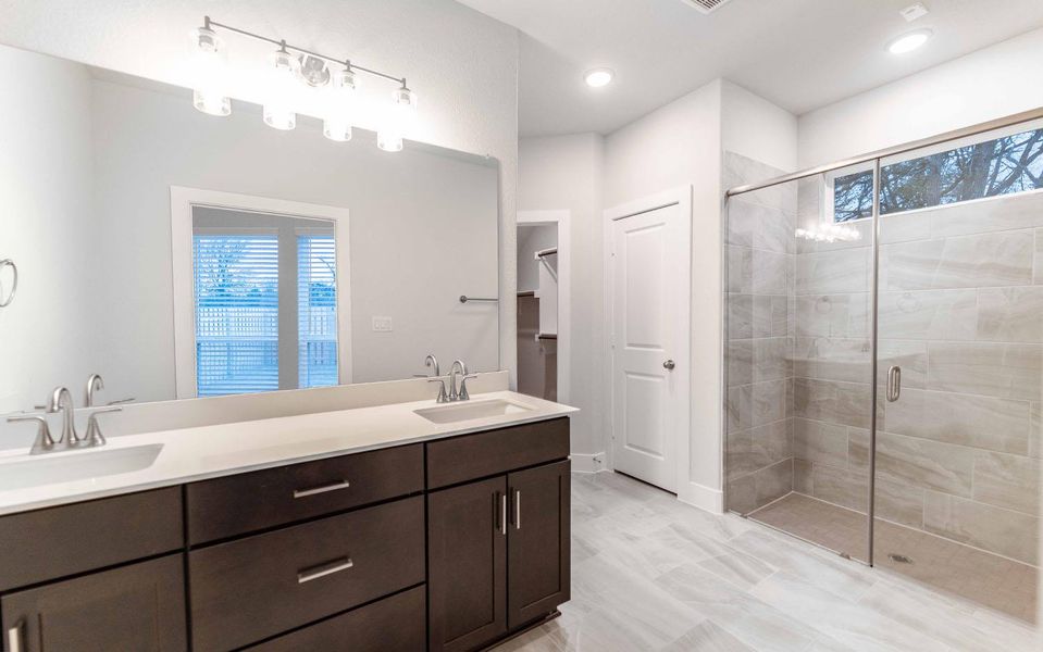 Full bath featuring a stall shower, a sink, and double vanity