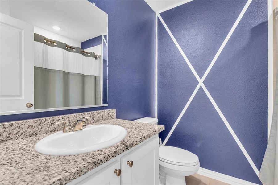 Full bath with a textured wall, vanity, and curtained shower