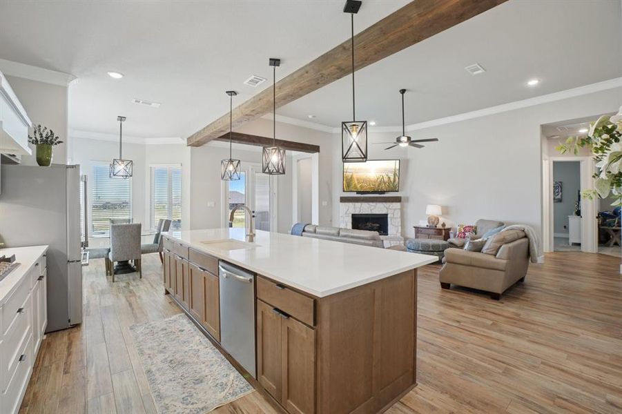 Kitchen with crown molding, light wood-look ceramic tile flooring, stainless steel appliances, and upgraded gas cooktop.