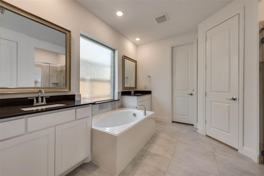 Bathroom featuring tile patterned floors, vanity, and a bathing tub