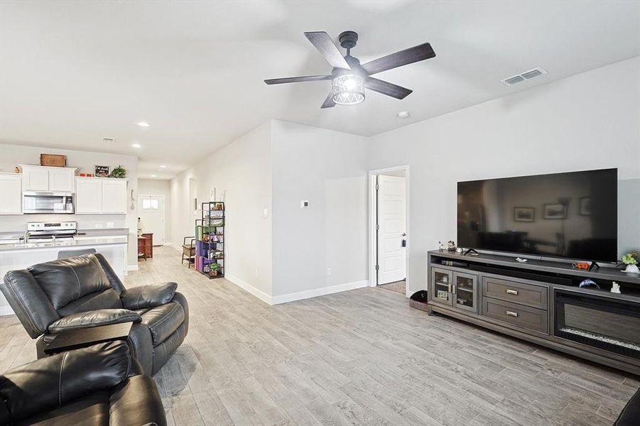 Living area with ceiling fan, light wood-style flooring, recessed lighting, visible vents, and baseboards