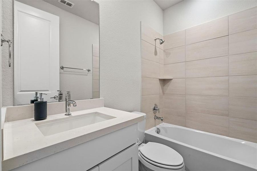 Full bathroom featuring tiled shower / bath, vanity, and toilet