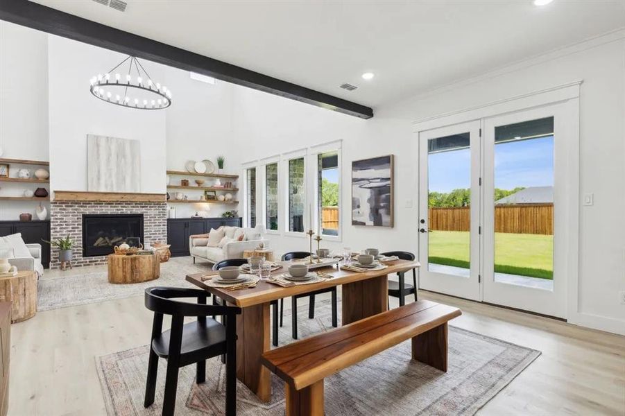 Dining space with light wood-type flooring, a brick fireplace, and suspended lighting