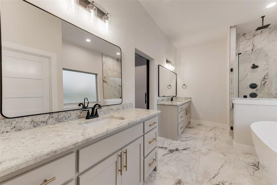 Full bathroom featuring light marble finish flooring, a marble finish shower, two vanities, a freestanding bath, and recessed lighting Full bathroom featuring light marble finish flooring, a marble finish shower, two vanities, a freestanding bath, and recessed lighting
