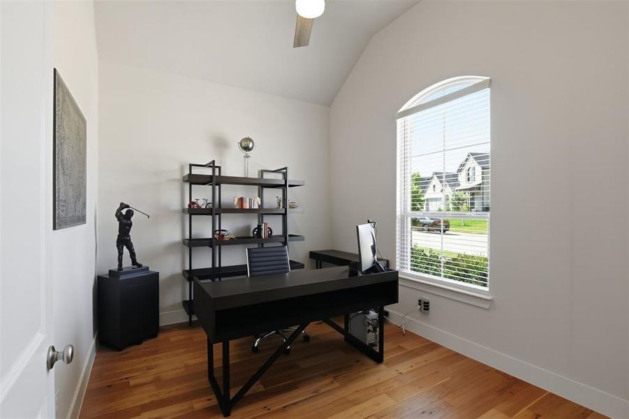 Bright room featuring an arched window, wood-finish flooring, a vaulted ceiling, and a ceiling fan with integrated lighting Bright room featuring an arched window, wood-finish flooring, a vaulted ceiling, and a ceiling fan with integrated lighting