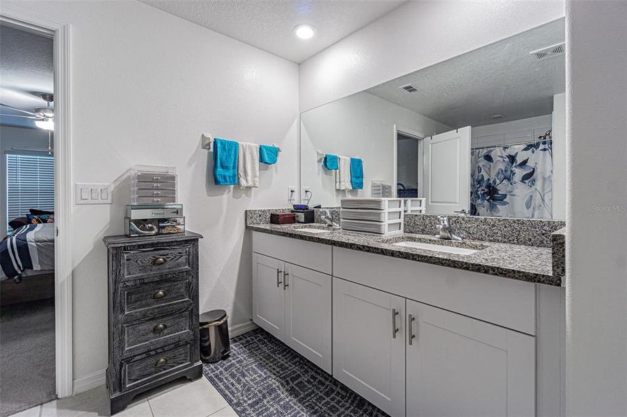 Double sinks, granite countertops, white shaker cabinets in primary bath