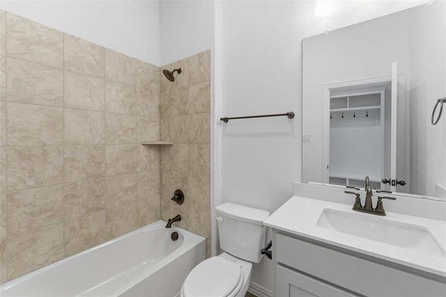 Bathroom featuring a white vanity with a rectangular sink, a large wall mirror, and a bathtub with tiled surround