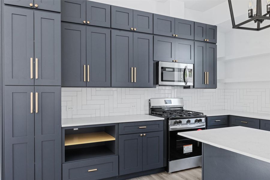 Kitchen featuring open shelves, appliances with stainless steel finishes, light stone countertops, and decorative backsplash Kitchen featuring open shelves, appliances with stainless steel finishes, light stone countertops, and decorative backsplash