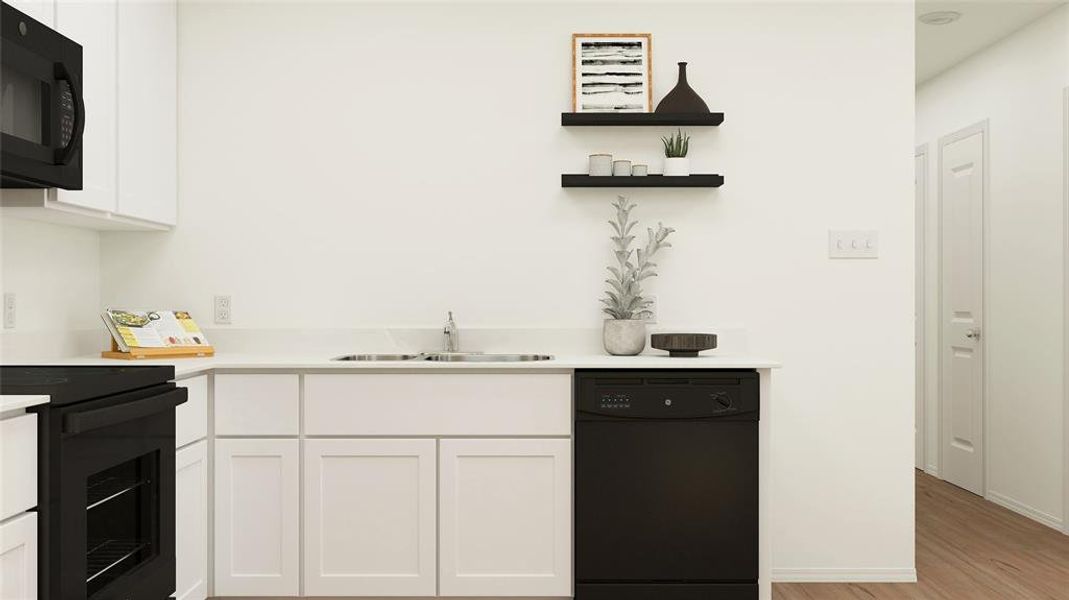 Kitchen featuring sink, white cabinets, black appliances, and light wood-type flooring