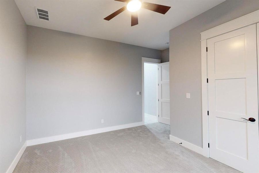 Unfurnished bedroom with light colored carpet and ceiling fan